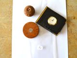 une petite boîte sur laquelle est posée une montre, à côté d'un petit objet marron