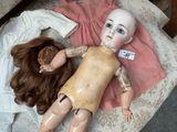 a doll laying on a bed next to a hairbrush