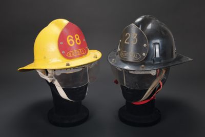 deux casques de pompier exposés sur un fond noir