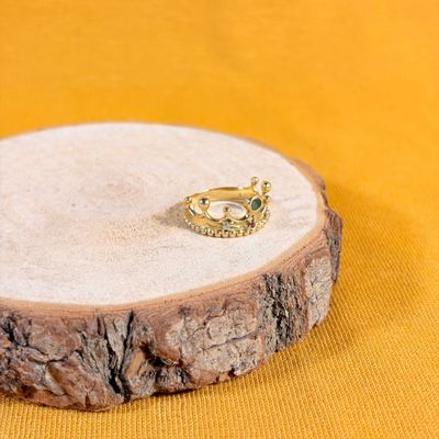 bague plaquée or posée sur un support en bois, sur fond jaune