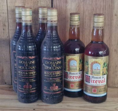 several bottles of wine are lined up on a wooden shelf