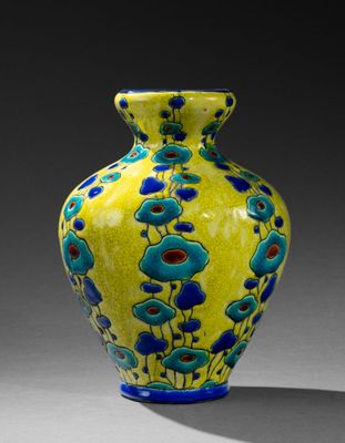 un vase jaune orné de fleurs bleues, posé sur une table
