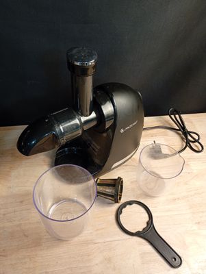 un extracteur de jus noir posé sur une table en bois