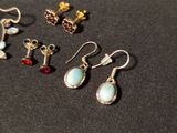 four pairs of earrings are sitting on a black surface