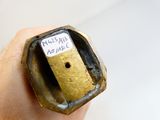 une main tenant un petit objet métallique muni d'une étiquette