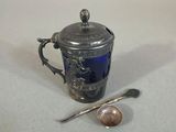 a small silver cup with a spoon and spoon rest next to it