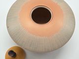 a small vase with a wooden lid next to a smaller vase