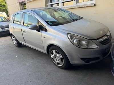 La voiture argentée est garée devant un immeuble, à côté d'une autre voiture garée.