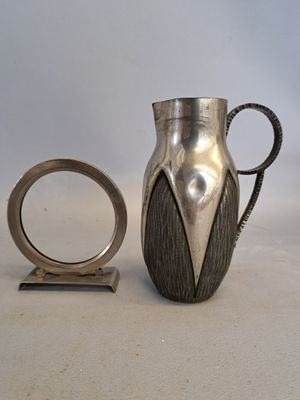 un pichet en argent posé à côté d'une bague sur une table