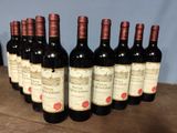 six bottles of red wine are lined up on a wooden table