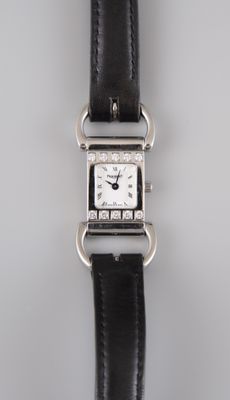 un gros plan d'une montre avec un bracelet noir posée sur une surface blanche