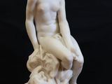 marble statue of a man sitting on a rock with his hands on his knees