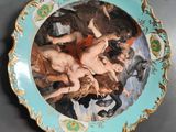 a plate with a painting on it sitting on a table