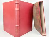un livre ouvert à couverture rouge posé sur une table blanche