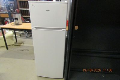 a white refrigerator sitting in a room with a black door