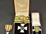 deux médailles et une croix sont rangées dans un écrin posé sur une table