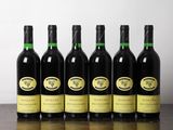 six bouteilles de vin sont posées sur une table devant un mur blanc