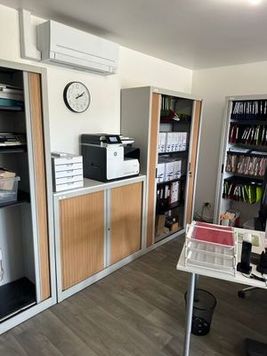une pièce avec un bureau, des étagères et une horloge accrochée au mur