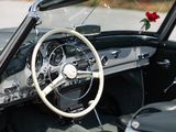 a steering wheel and dashboard of a car with a rose in the window