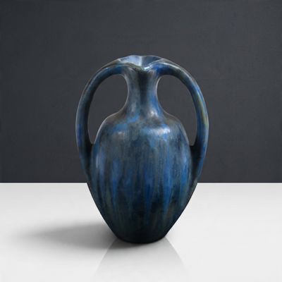 un vase bleu posé sur une table, sur fond noir