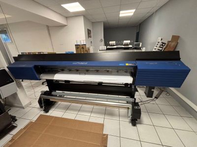 une grande imprimante dans une pièce où se trouve un carton posé par terre