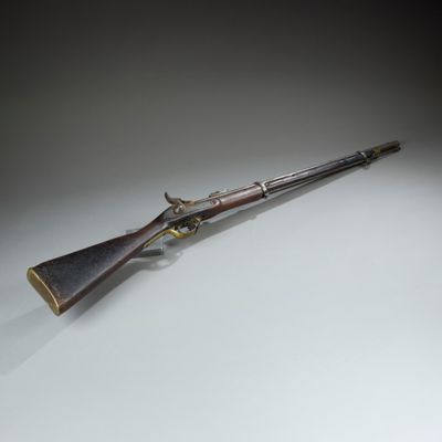 an old rifle with a wooden barrel on a white surface
