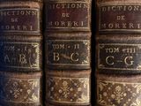 several old books are stacked on top of each other on a shelf