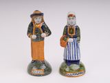 two figurines of people standing next to each other on a white surface