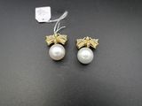 une paire de boucles d'oreilles en perles et en or posées sur un fond noir