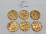 six gold sovereigns of different sizes and shapes are on a white surface