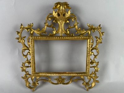 une photo représentant un cadre doré accroché à un mur blanc