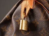 a close up of a louis vuitton bag with a padlock on it