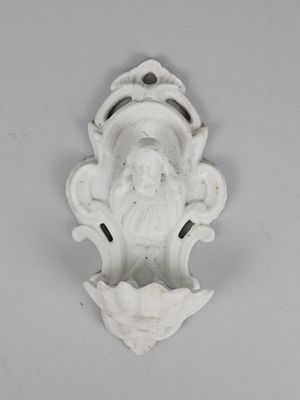 une vieille statue blanche représentant un homme barbu, posée sur un mur