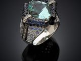 a blue and white diamond ring on a black surface