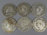 six different types of silver coins are shown on a gray surface