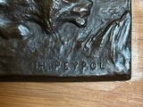a bronze plaque of a bear on a wooden table