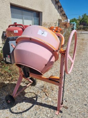 a pink cement mixer sitting in front of a building