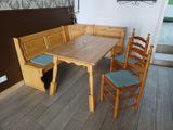 a wooden table with four chairs and a bench in the corner