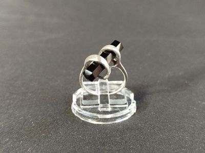 a small black and white ring on top of a clear stand