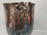 un vase en argent orné d'une tête de chèvre, exposé