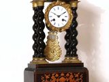 une horloge noire et dorée posée sur une étagère blanche
