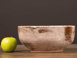 a green apple sitting next to a bowl on a table