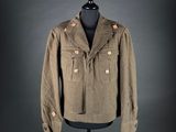 an old military jacket on a mannequin stand on a black background