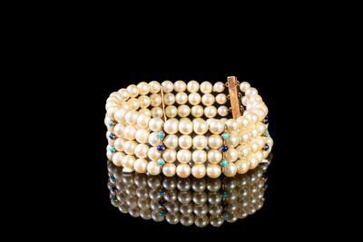 un gros plan d'un bracelet orné de perles sur un fond noir