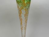 un vase en verre vert et or posé sur une surface blanche