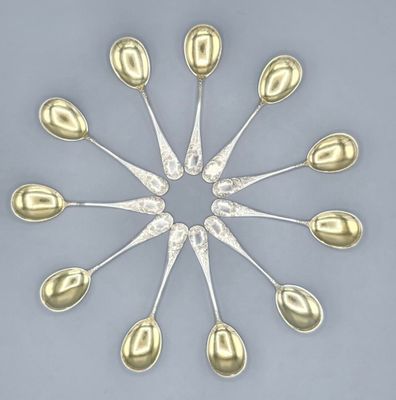 six cuillères en argent disposées en cercle sur une surface grise