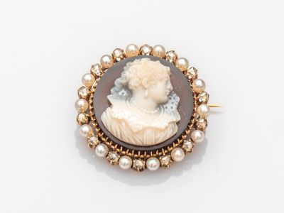 un gros plan sur une broche représentant une femme avec des perles
