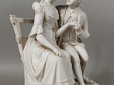 une statue représentant une femme et un homme assis sur un banc
