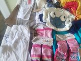 a pile of baby clothes and shoes on a bed
