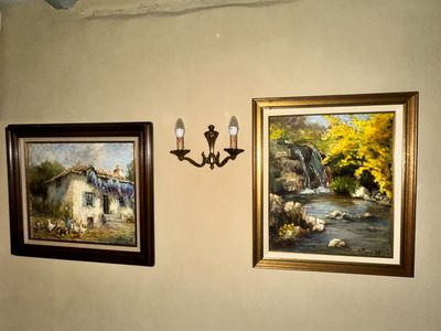 two paintings on the wall above a toilet in the bathroom